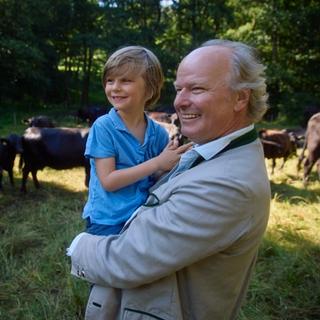 Stefan carrying his son in a field with cows
