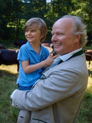 Stefan carrying his son in a field with cows