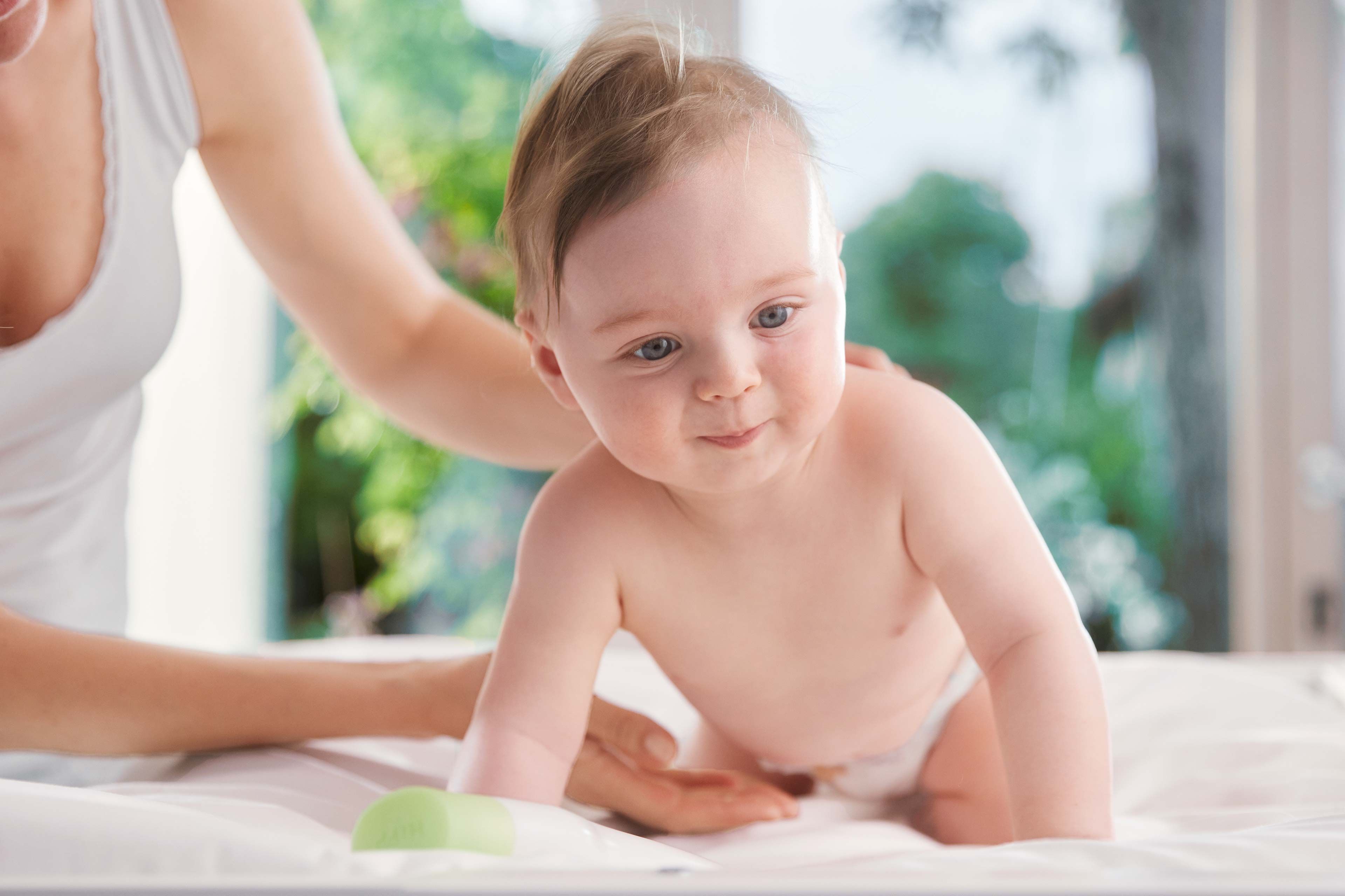 Ein Baby mit blauen Augen, das direkt in die Kamera schaut, während es von einem Erwachsenen gehalten wird.