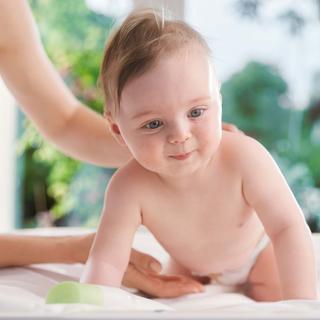 Ein Baby mit blauen Augen, das direkt in die Kamera schaut, während es von einem Erwachsenen gehalten wird.