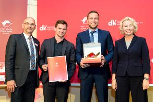 HiPP Vertreter nehmen vor rotem Hintergrund den Deutschen Verpackungspreis 2016 entgegen und präsentieren Urkunde und Trophäe.