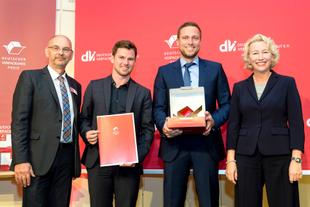 HiPP Vertreter nehmen vor rotem Hintergrund den Deutschen Verpackungspreis 2016 entgegen und präsentieren Urkunde und Trophäe.