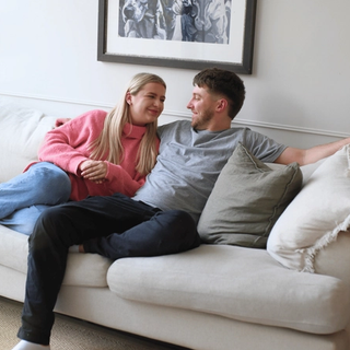 women and man sitting on a couch looking at each other and smiling.