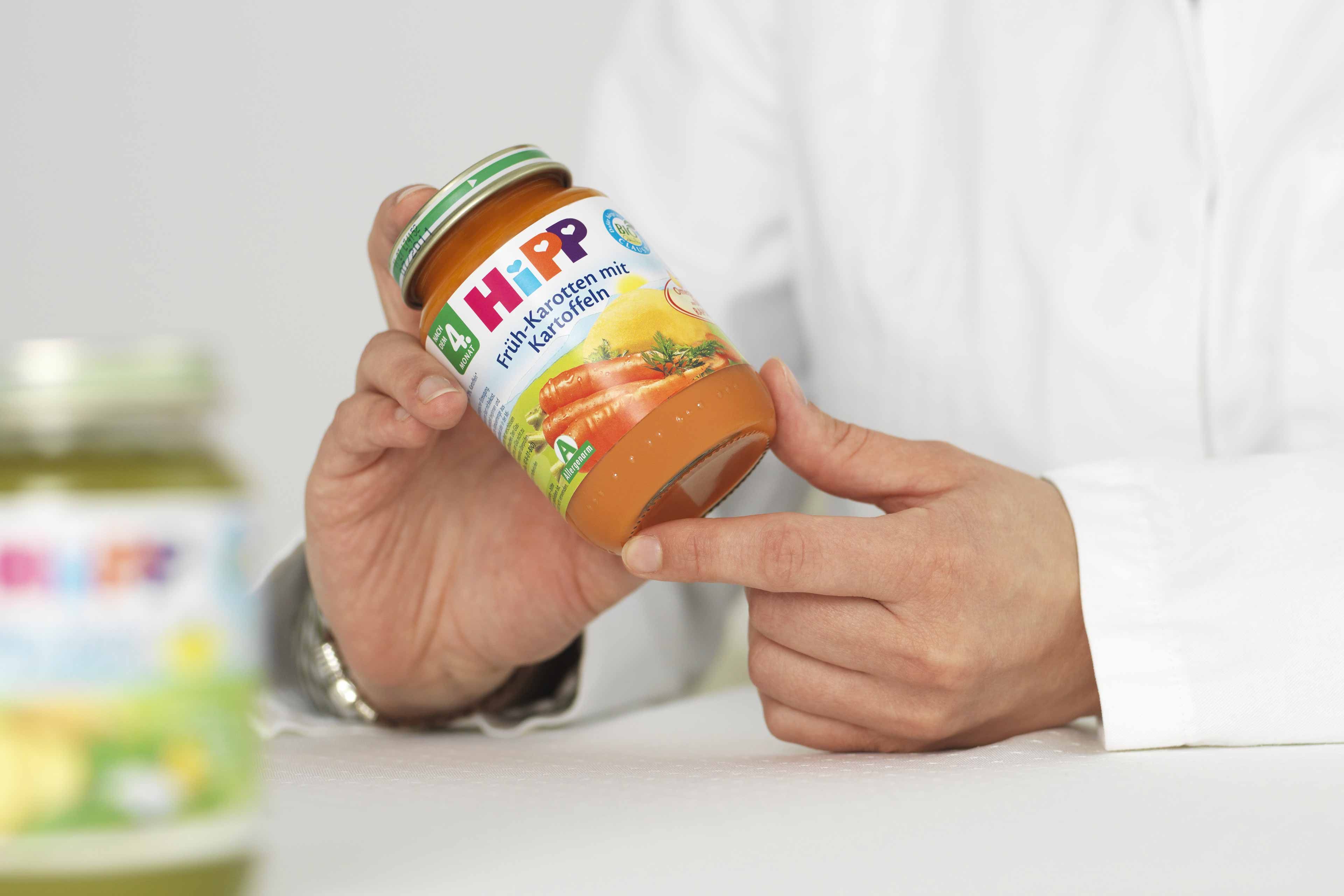 Person hält ein Glas mit einem Etikett, auf dem 'HiPP' steht