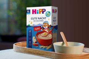 Hipp Gute Nacht Bio Milchbrei auf einem Holztablett vor unscharfem Hintergrund