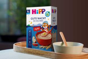 Hipp Gute Nacht Bio Milchbrei auf einem Holztablett vor unscharfem Hintergrund