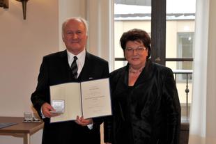 Prof. Dr. Claus Hipp steht mit Landtagspräsidentin Barbara Stamm, hält Urkunde und Etui zur Bayerischen Verfassungsmedaille in Gold.