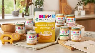 An array of HiPP's baby food on a kitchen worktop, alongside a bowel, spoon and baby toy.