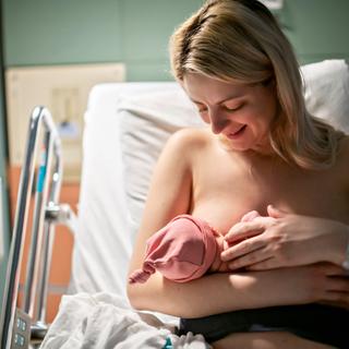 Ein zärtlicher Moment zwischen einer Mutter und ihrem neugeborenen Baby in einem Krankenhaus.