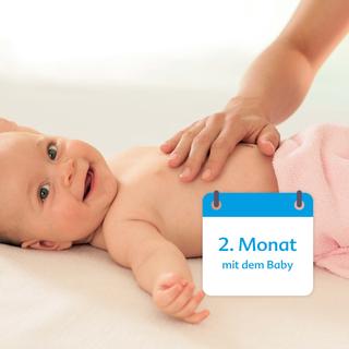Ein Baby liegt auf einer weichen Unterlage, die Hand einer Person berührt sanft seinen Rücken, begleitet von einer kalenderähnlichen Grafik mit der Aufschrift "2. Monat mit dem Baby".