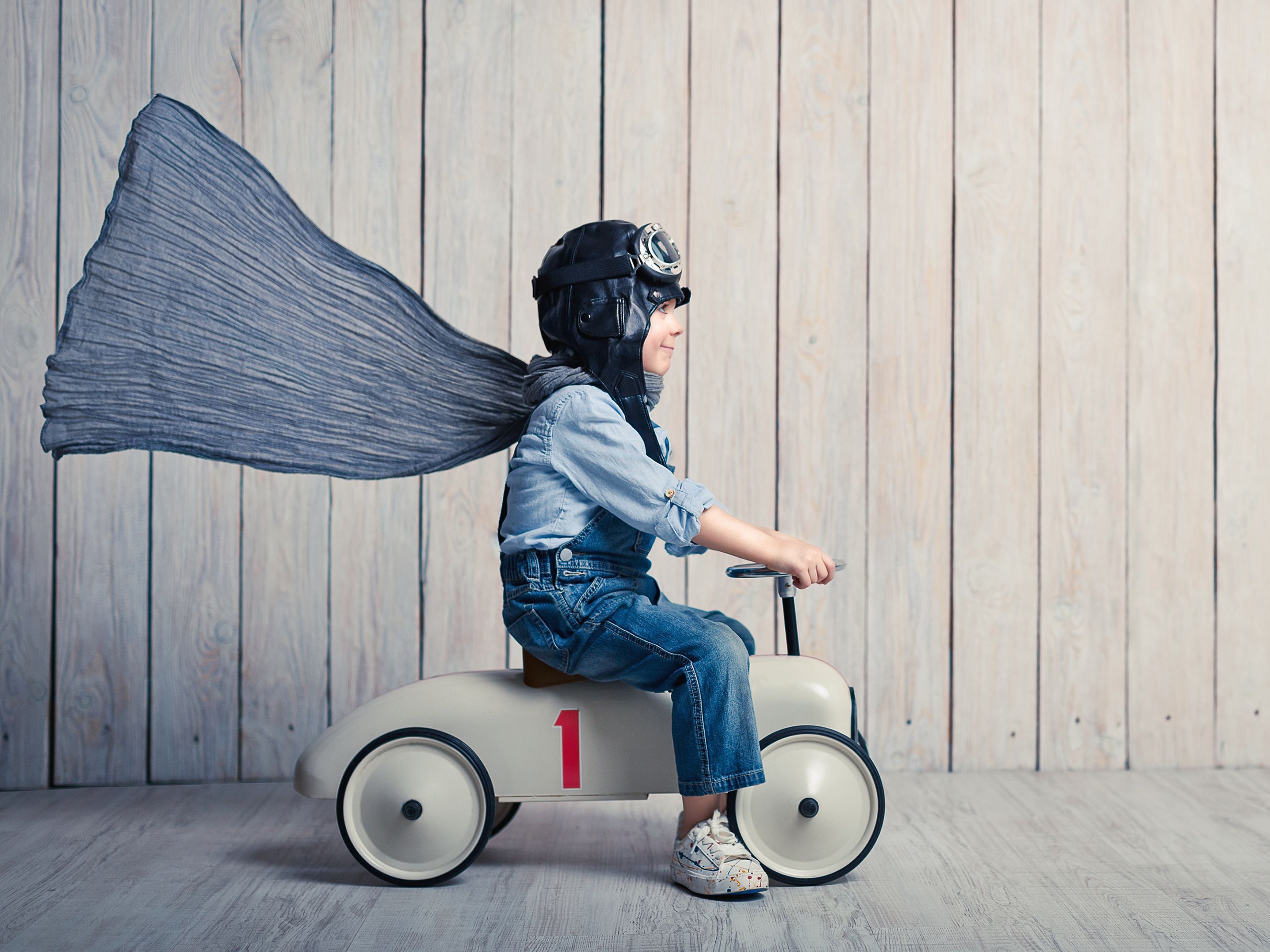 Kind mit Piloten Outfit fährt auf Bobbycar