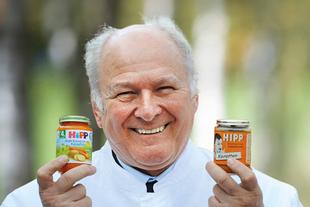 Älterer Mann lächelt und hält ein modernes HiPP Bio-Babygläschen und ein historisches HiPP-Glas als Vergleich in den Händen.