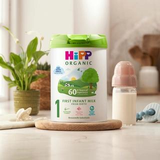 HiPP Organic First Infant Milk Powder Tin on a kitchen worktop next to a bottle of milk