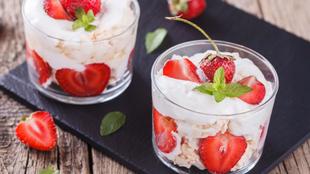Zwei Gläser, gefüllt mit einem cremigen Dessert, garniert mit frischen Erdbeeren und Minzblättern.
