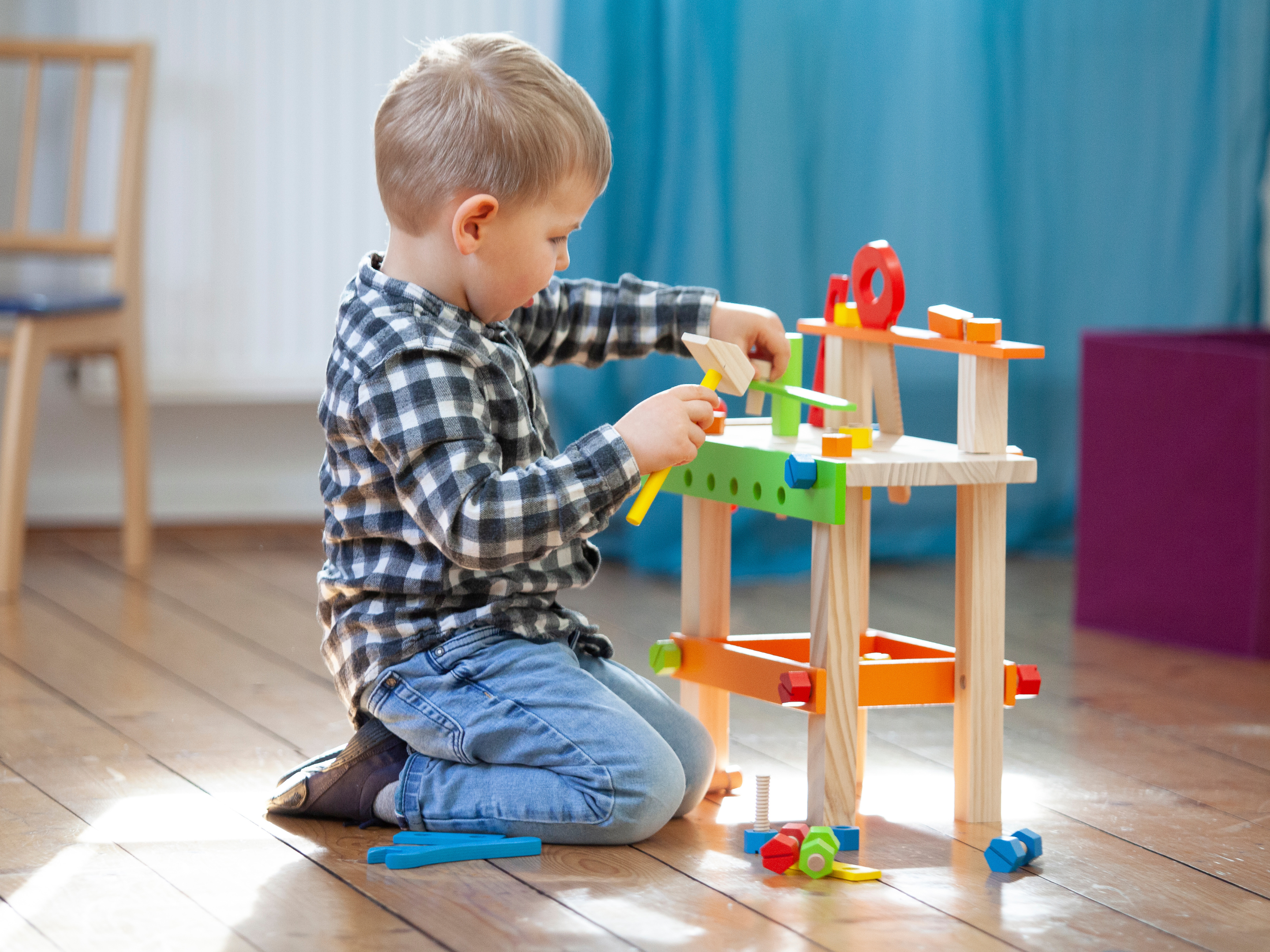 Kleines Kind spielt auf dem Boden mit Holzspielturm