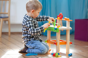 Kleines Kind spielt auf dem Boden mit Holzspielturm