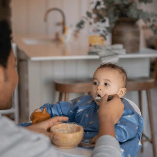 Dad feeding baby porridge