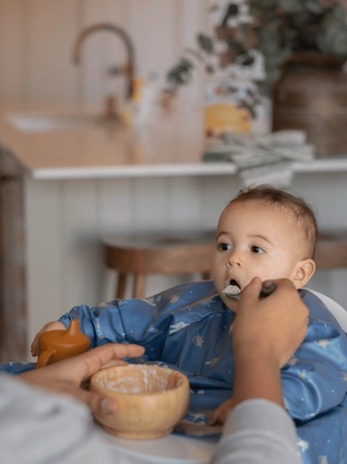 Dad feeding baby porridge