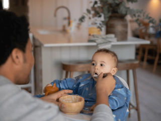 Dad feeding baby porridge
