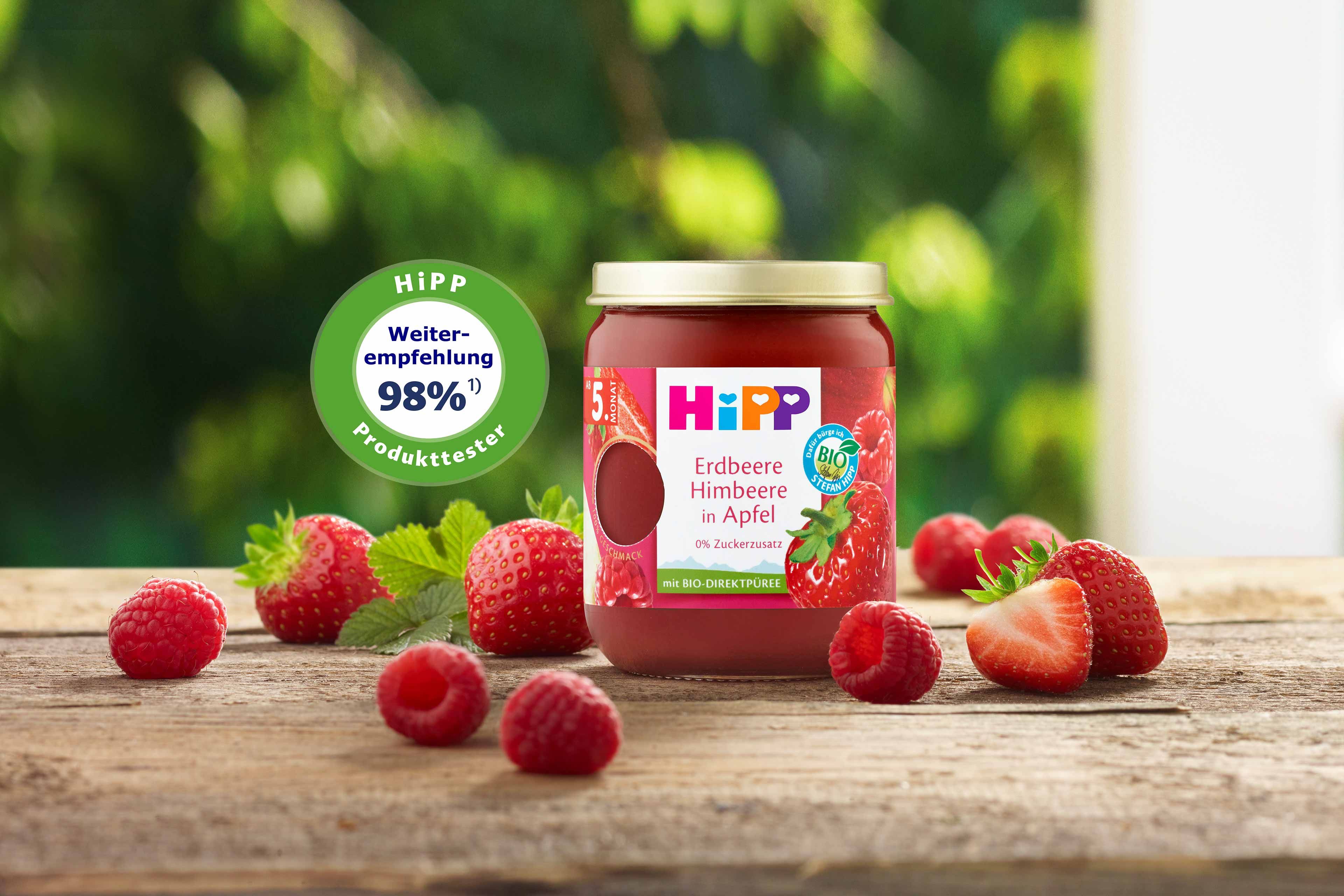 HiPP Premium Früchte Gläschen „Erdbeere Himbeere in Apfel“ mit 98 % Weiterempfehlungssiegel, umgeben von frischen Erdbeeren und Himbeeren.