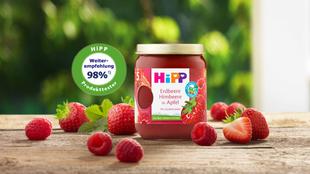 HiPP Premium Früchte Gläschen „Erdbeere Himbeere in Apfel“ mit 98 % Weiterempfehlungssiegel, umgeben von frischen Erdbeeren und Himbeeren.