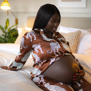 Pregnant mum sat on the end of the bed rubbing her bump