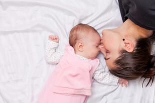 Ein zärtlicher Moment zwischen einer Mutter und ihrem Baby, in dem die Mutter sanft die Stirn des Babys küsst.