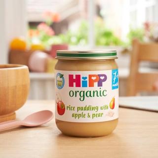 HiPP Organic Rice Pudding with Apple & Pear on a dining table next to a bowl and spoon