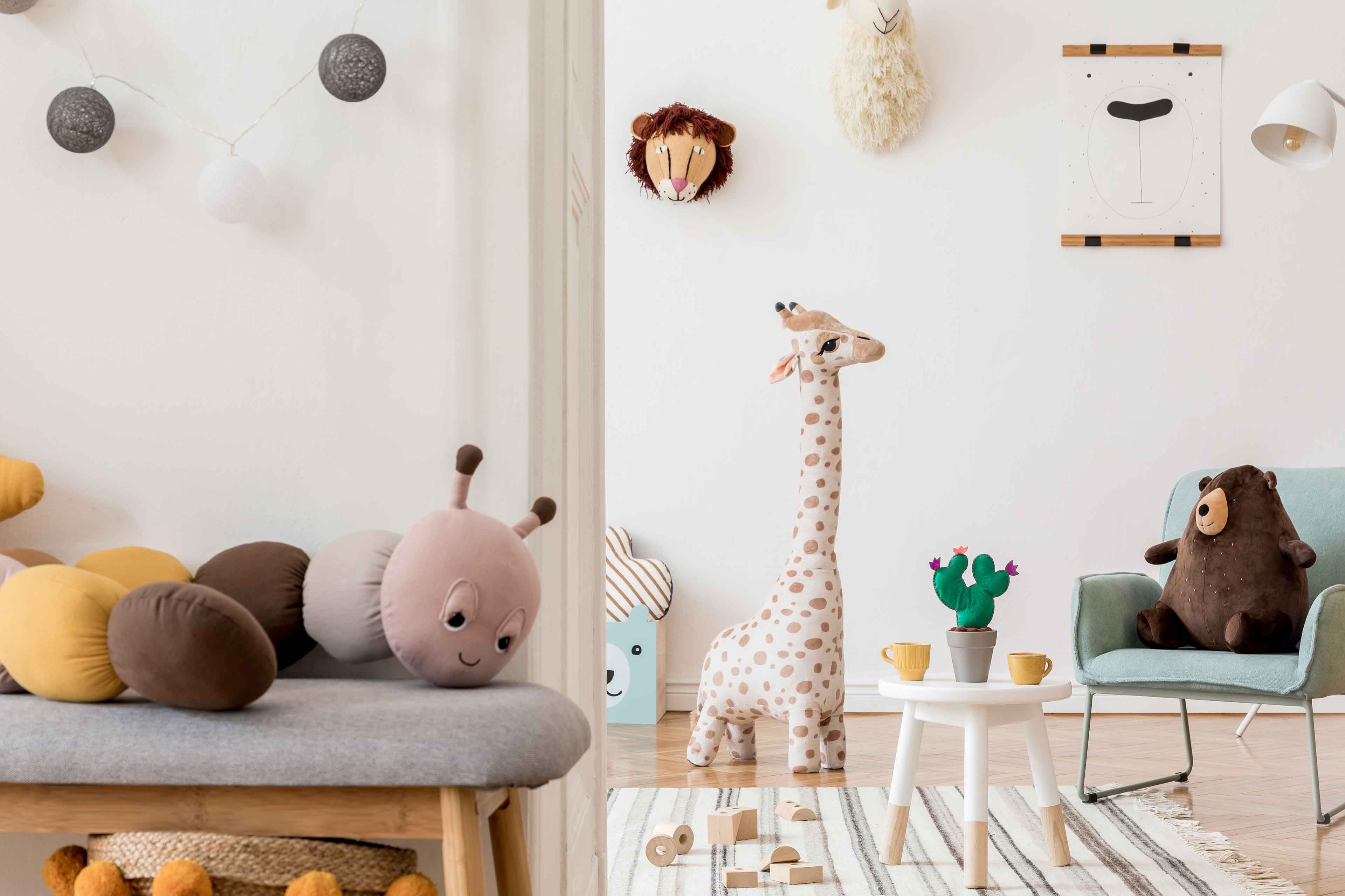 Ein gemütliches Kinderzimmer mit Plüschtieren, einer Giraffe, einem Teddybär und dekorativen Elementen.