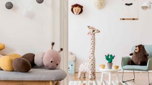 Ein gemütliches Kinderzimmer mit Plüschtieren, einer Giraffe, einem Teddybär und dekorativen Elementen.