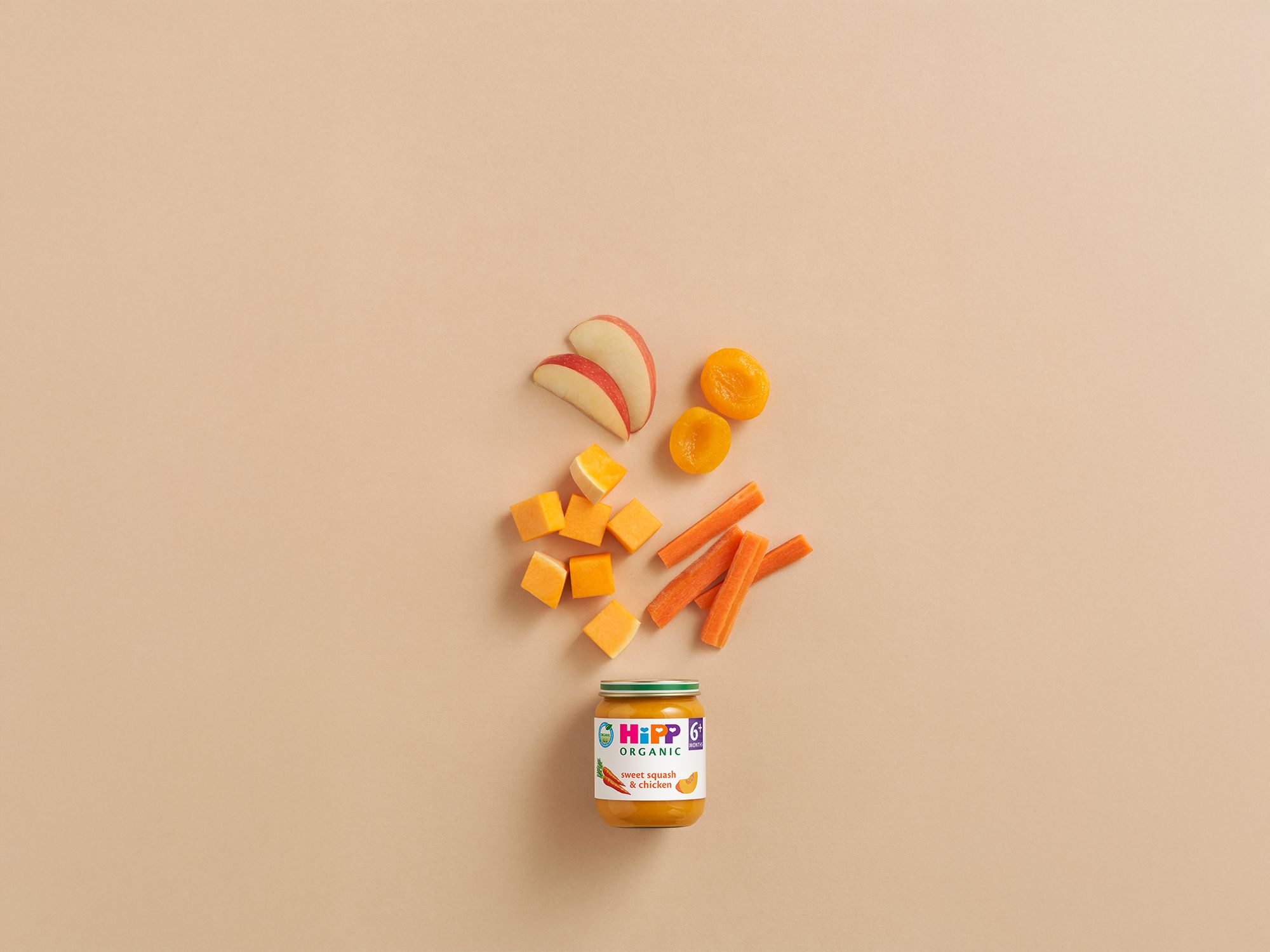 HiPP Organic Sweet Squash & Chicken baby food jar with apple slices, apricot halves, squash cubes and carrot sticks on a neutral background