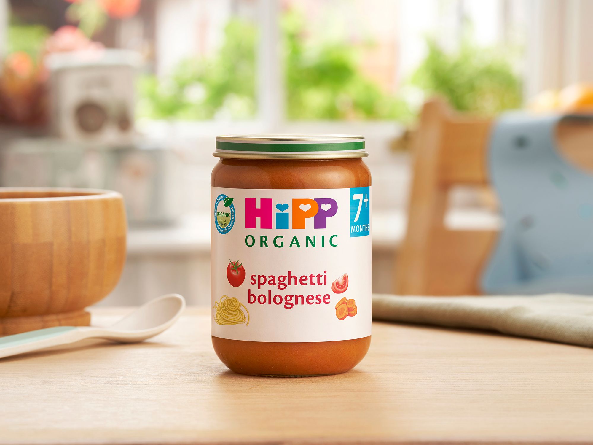 HiPP Organic Spaghetti Bolognese on a dining table next to a bowl and spoon