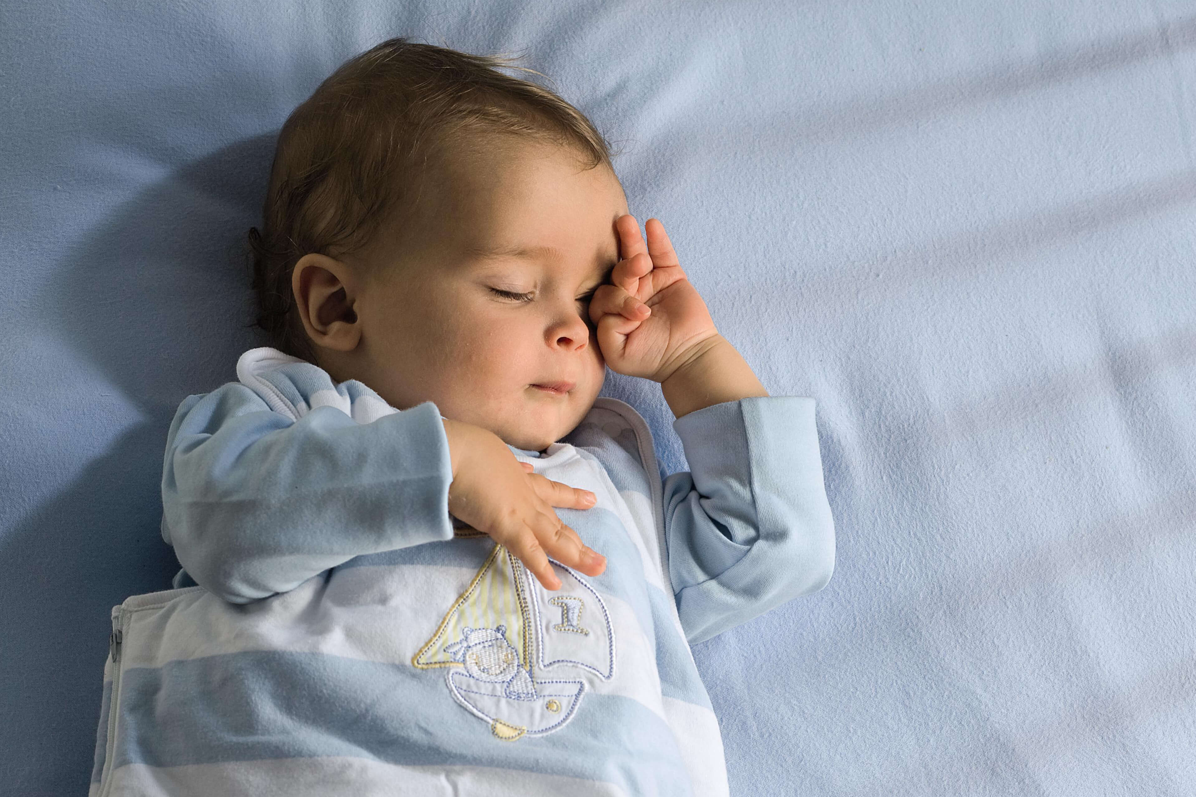 Ein Baby, das scheinbar tief schläft und dessen Gesicht von einer Hand sanft berührt wird.