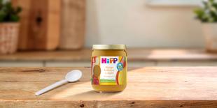 HiPP Bio-Früchte-Gläschen Mango Erdbeere in Apfel ab 6 Monaten auf Holztisch mit Löffel in heller Küche