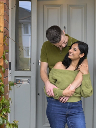 A couple hugging in front doorway