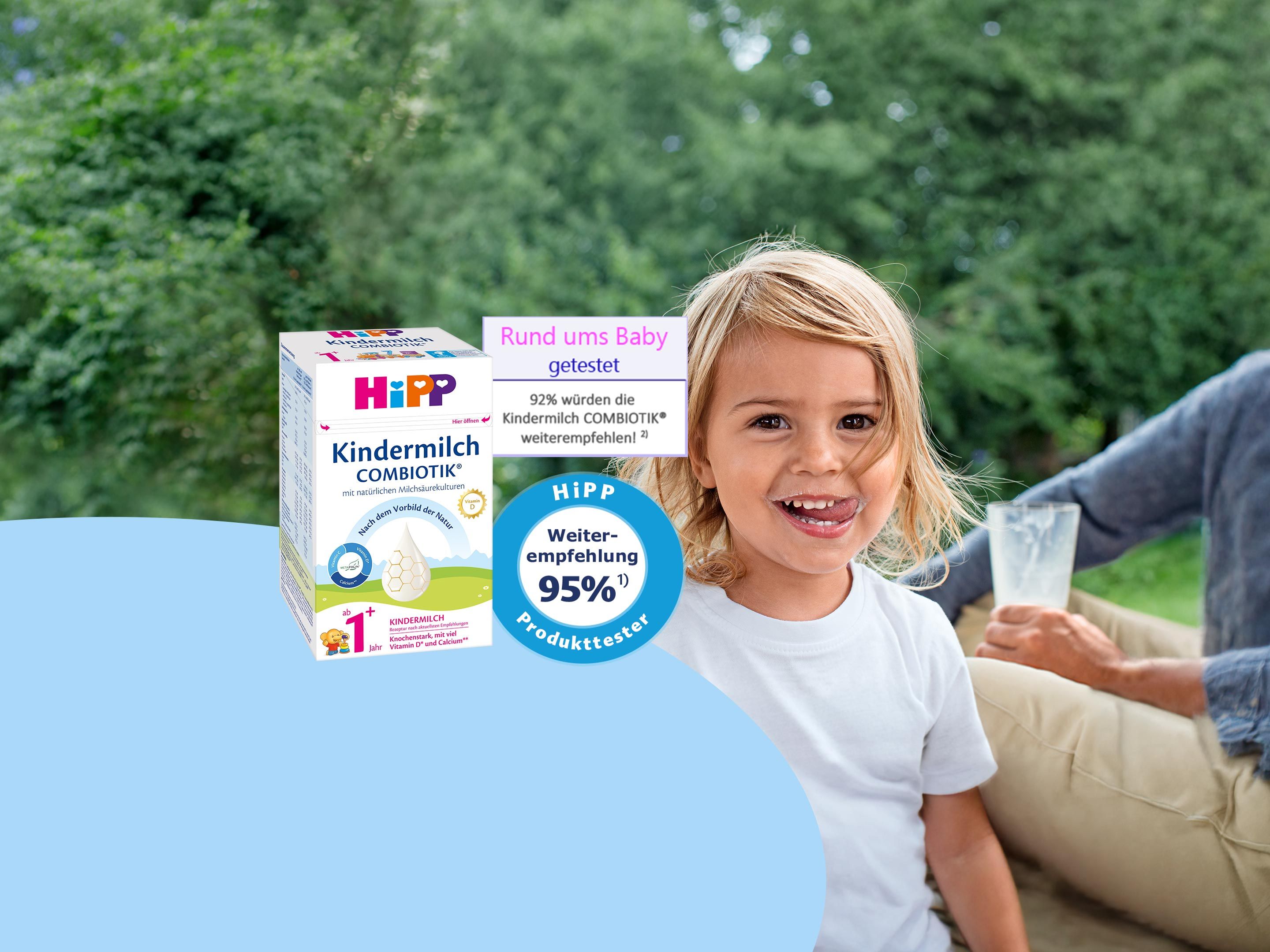 Lachendes Kleinkind mit Glas Milch neben HiPP Kindermilch COMBIOTIK Packung und Rund ums Baby Produkttest-Siegel im Garten