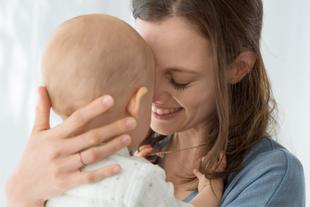 Mutter hält ihr Baby nach dem Abstillen eng im Arm und kuschelt liebevoll Stirn an Stirn
