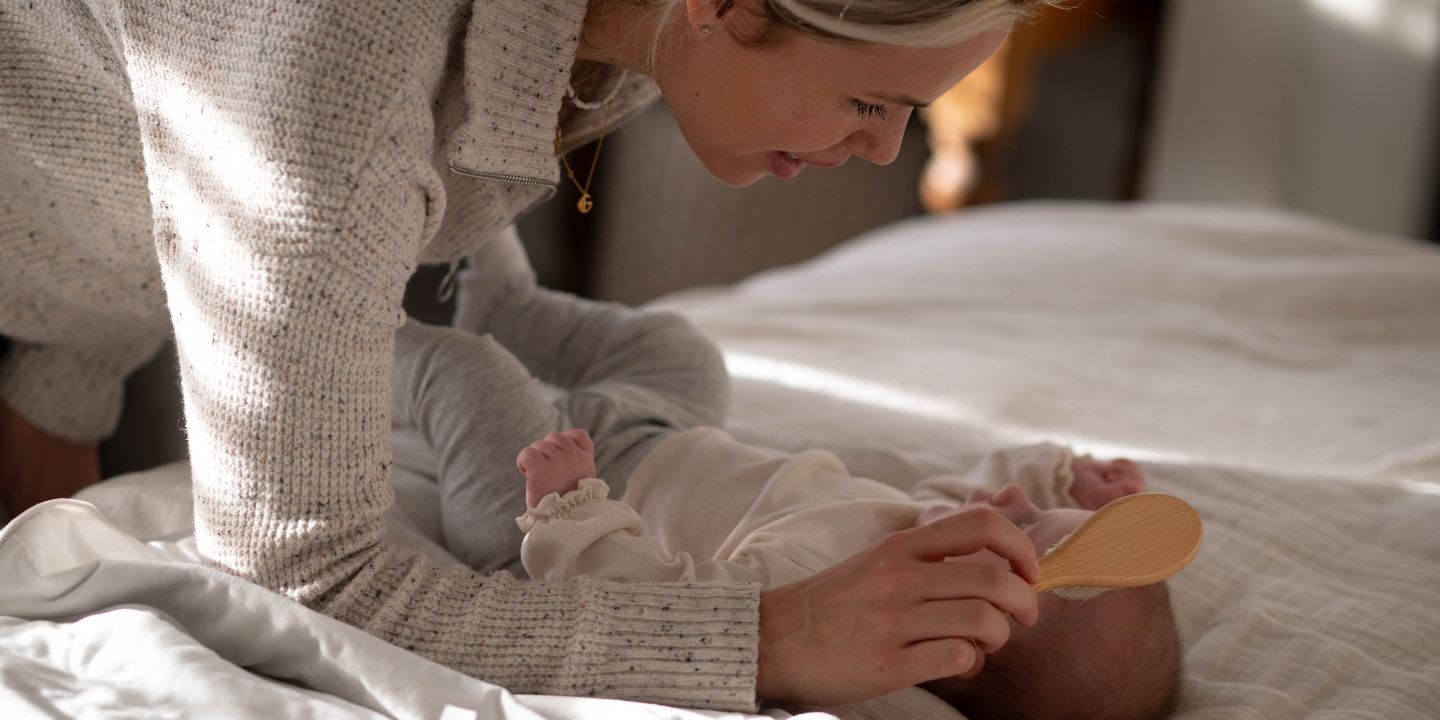 Mum brushing newborn baby's hair