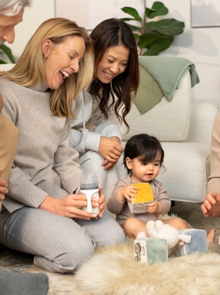 Family watching baby play with toys