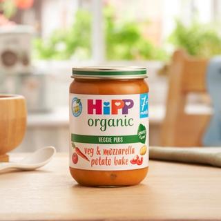 HiPP Organic Veg & Mozzarella Potato Bake on a dining table next to a bowl and a spoon
