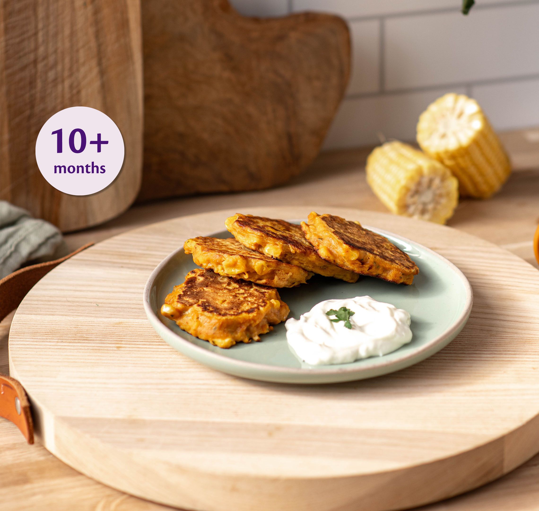 Tuna and sweetcorn fritters on a small plate with a dollop of dip, suitable as finger food for babies 10 months and over