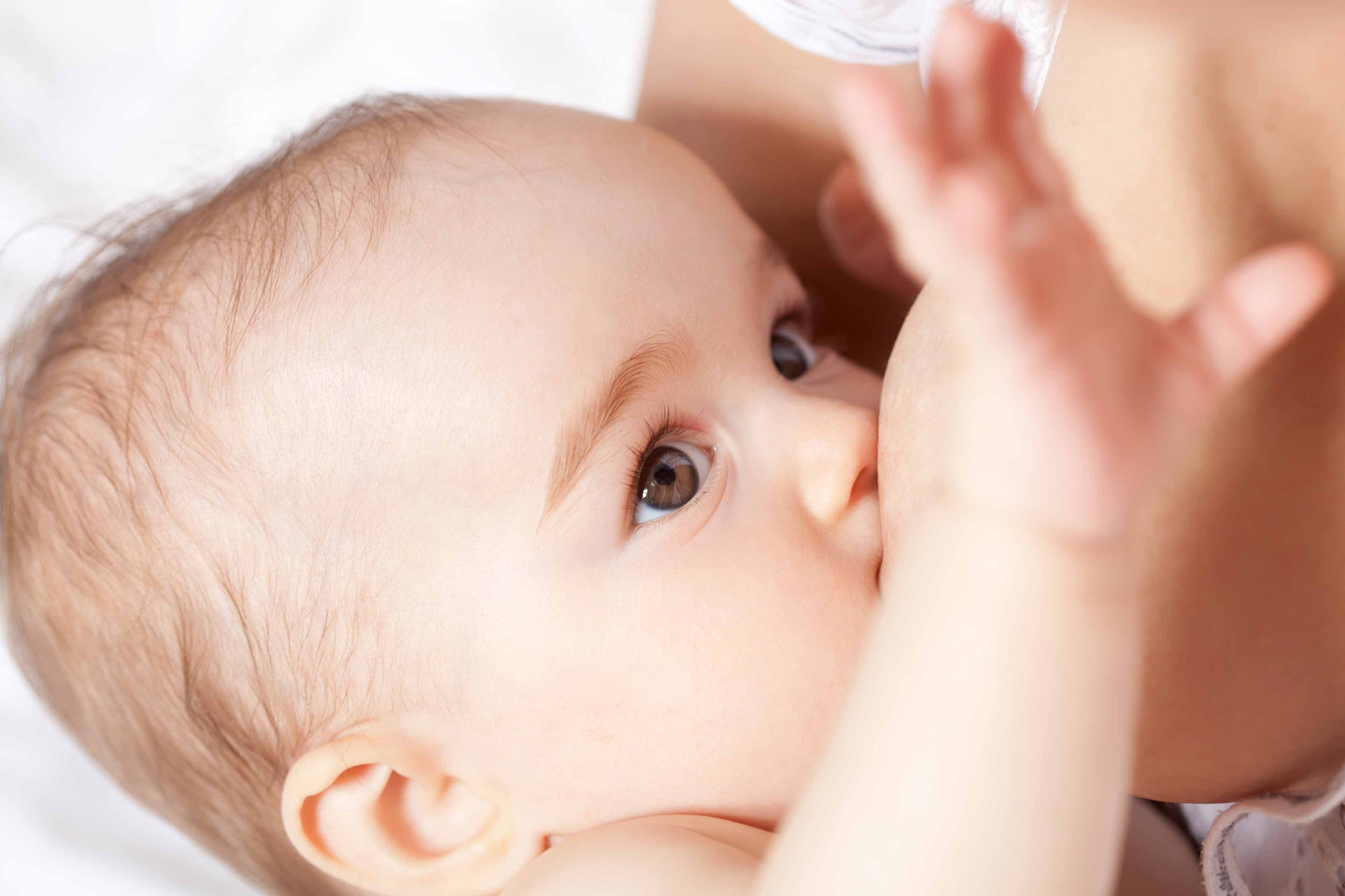 Nahaufnahme eines Babygesichts mit Schwerpunkt auf den Augen und der Mundpartie, wobei eine Hand nach dem Baby greift.