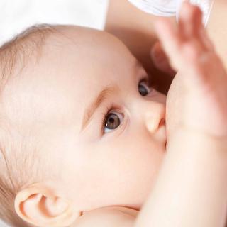 Nahaufnahme eines Babygesichts mit Schwerpunkt auf den Augen und der Mundpartie, wobei eine Hand nach dem Baby greift.