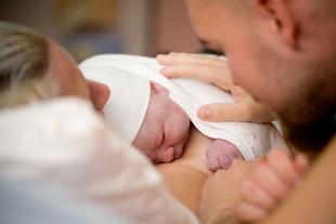 Ein zärtlicher Moment zwischen einer Mutter und einem Vater, die ihr neugeborenes Baby im Arm halten.