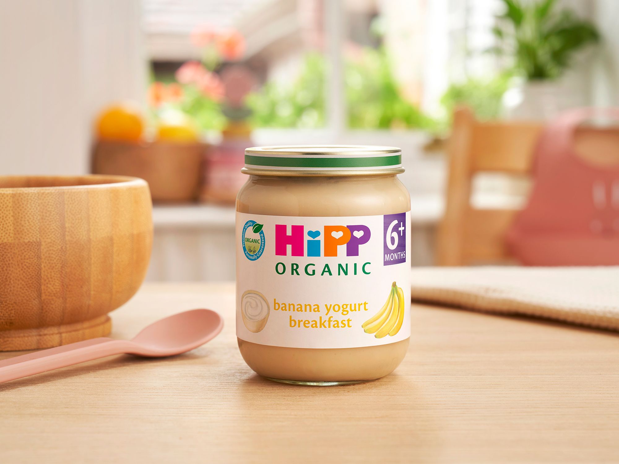 HiPP Organic Banana Yogurt Breakfast jar on a dining table next to a bowl and spoon