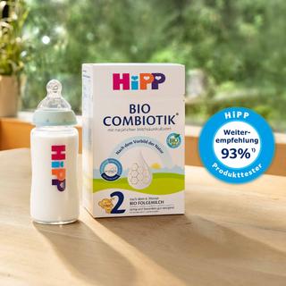 HiPP BIO COMBIOTIK® 2 Folgemilch mit Babyflasche auf Holztisch, daneben Siegel „HiPP Produkttester – Weiterempfehlung 93 %“ vor grünem Hintergrund.