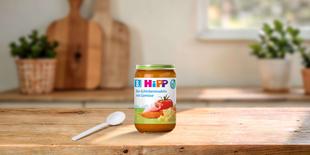 HiPP Bio-Schinkennudeln mit Gemüse 220g im Glas auf Holztisch mit Löffel in heller, gemütlicher Küche