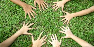 Mehrere Hände bilden einen Kreis auf grünem Gras