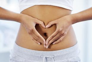 Eine Person formt eine Herzform mit ihren Händen über dem Bauch.