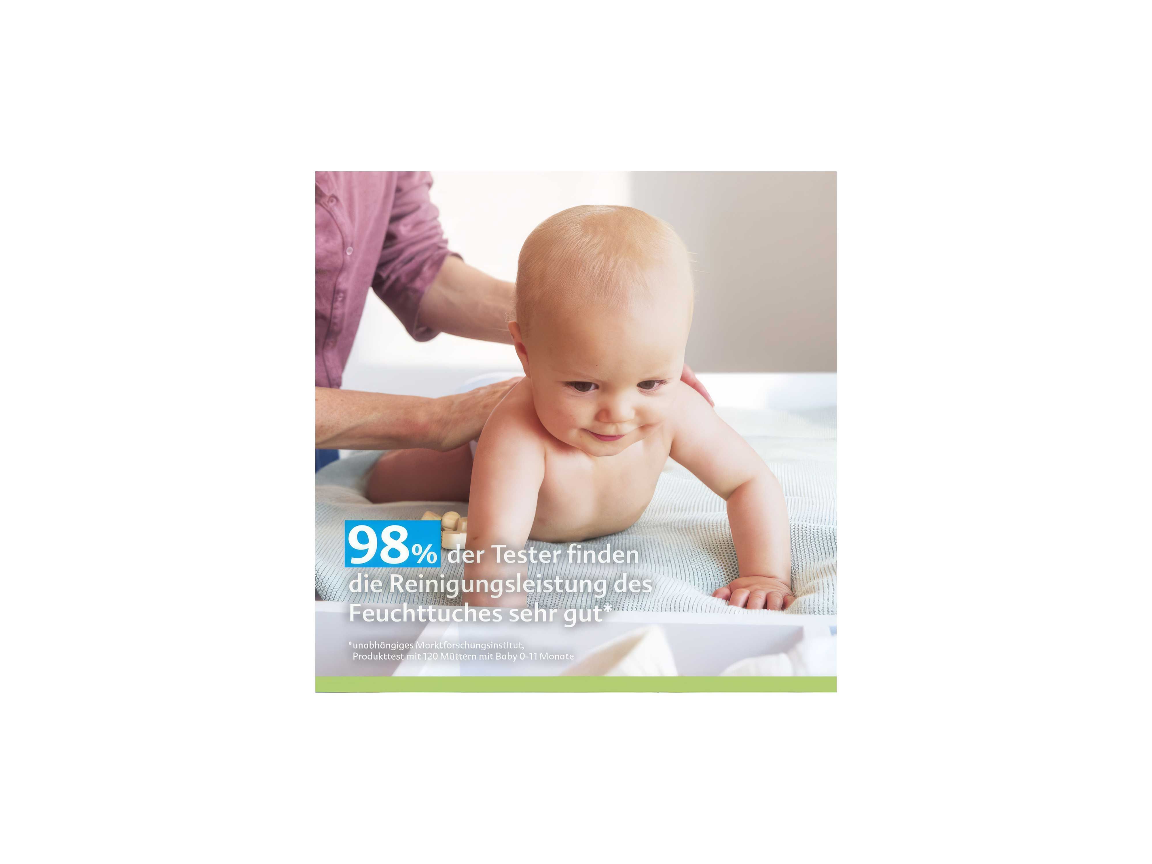 Ein Baby liegt auf dem Bauch auf einer weichen Unterlage. Im Hintergrund ist ein erwachsener Arm zu sehen, der das Baby sanft hält. Links unten steht in großer, weißer und blauer Schrift: '98 % der Tester finden die Reinigungsleistung des Feuchttuches sehr gut'. Der Hintergrund ist hell und freundlich gestaltet.